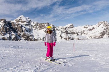 Yakın plan mutlu kız Avrupa Alplerinde kış anlarının tadını çıkarıyor. Karlı tepenin arka planı. Neşeli kış kızı. Kış sporu ve etkinliği. 