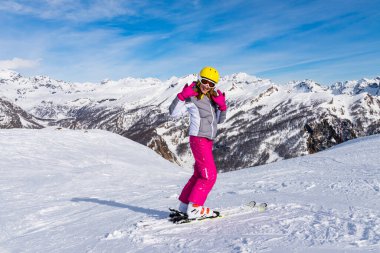 Genç bayan kayakçı yokuş aşağı inmeye hazırlanıyor. Alpe Devero, Piedmont, İtalya 'da kayak merkezi. Kış sporları. 