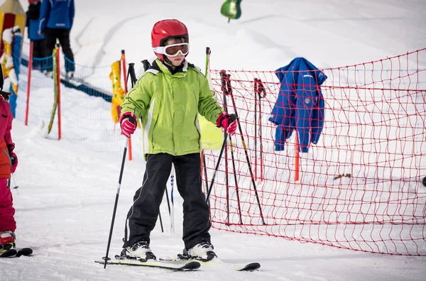子供は冬の休暇中に山の斜面でスキーをする方法を学ぶ 安全ヘルメットとゴーグルとアクティブな子供 アルペンスクールでのキッズスキーレッスン 雪の中の小さなスキーヤーレース — ストック写真