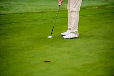 Close-up of a golf player who with a putt pocket the ball on the green clipart