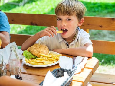 Güneşli bir günde bir çocuk tarafından yenmiş lezzetli bir hamburger..