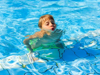Güneşli bir günde havuzda oynayan bir çocuk