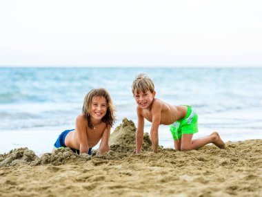 Mayo giymiş bir çocuk güneşli bir günde kumsalda oynar..