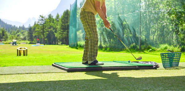 Игрок в гольф в клетчатых штанах тренирует свои качели для гольфа, вид сзади 