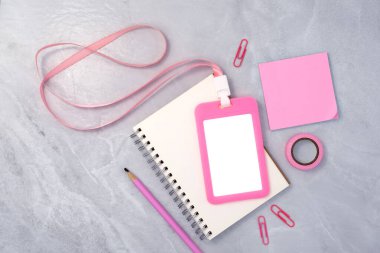 Beyaz taş desenli arka planda kitap ve kırtasiye malzemesi olan pembe plastik rozet. Şirket çalışanları için dizayn edilmiş şablon
