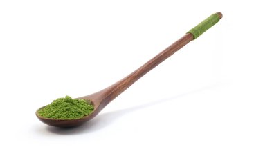 Beyaz arka planda izole edilmiş ahşap kaşıkta kibrit yeşil çay tozu