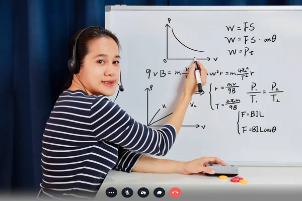 Asian school woman teacher working from home teach online math to student studying from home. Teacher writeing on whiteboard and talk on headset internet education class during covid19 pandemic