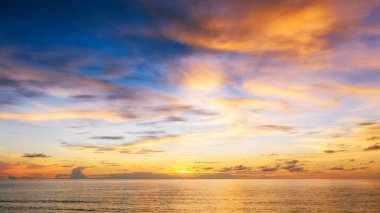 Deniz kabuğu üzerinde bulutlu ve gökyüzü arkaplanlı güzel bir gün batımı. Tropik sahilde gün batımı. Doğal yaz konsepti. Sarı ışıkla günbatımının zirvesi bulutları yansıtır.