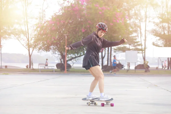 美しい夏の日に屋外のスケートボード上のアジアの女性 幸せな若い女性は朝の時間に公園でサーフィンをする スポーツ活動ライフスタイルコンセプト — ストック写真