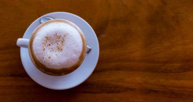 Üst manzara sıcak espresso kahvenin yakın plan beyaz bir seramik fincan içinde ahşap masa arka planı. 