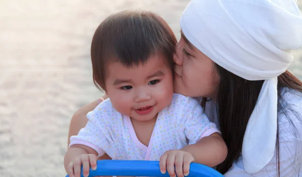 特写美丽的亚洲年轻母亲在公园亲吻她的小宝宝 快乐可爱的母亲吻她的小女儿 笑着的小女孩和她妈妈在操场上玩耍 — 图库照片