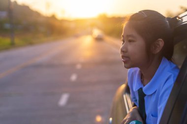 Arabadan dışarı bakan Asyalı küçük bir kız. Sabahleyin, kız okula giderken araba penceresinin dışında bir şeye bakıyordu. Çocuklar arabadan sokak manzarasıyla rahatlar. Aile araba konseptinde.
