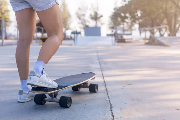 Close-up Asian women surf skate or skateboard outdoors on beautiful morning. Happy young women play surf skate at ramp park on morning time. Close up Asian women leg wear sneaker play surf skate on public park. Sport concept
