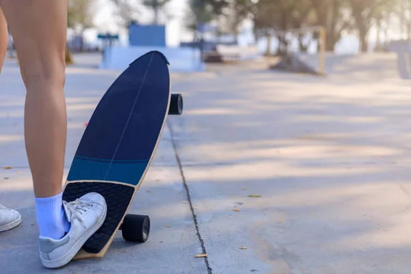 Close-up Asian women surf skate or skateboard outdoors on beautiful morning. Happy young women play surf skate at ramp park on morning time. Close up Asian women leg wear sneaker play surf skate on public park. Sport concept