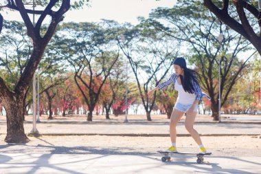 Genç Asyalı kadınlar parktaki kaykay rampasında kaykay oynuyorlar. Mutlu kadınlar parkta sörf tahtası oynarlar. Spor aktivitesi yaşam tarzı kavramı