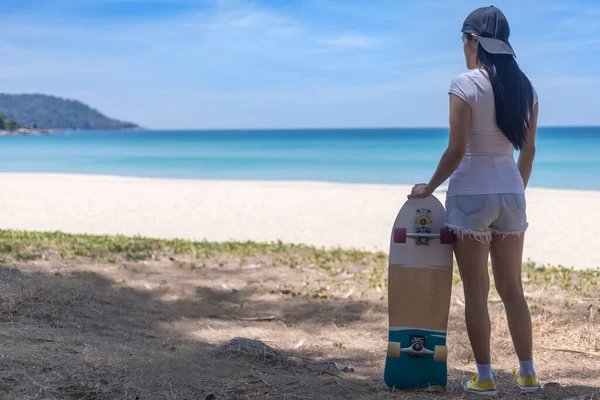 Young women hold surf skate board with beach background. Women stand with surf skate relax and enjoy with tropical beach with copy space