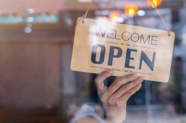 Asyalı perakendecinin eli, kafeteryadaki kadının tabela açması. Koronavirüs salgınına karşı koruma. Covid-19 karantinası nedeniyle açık dükkan, restoran veya bar.