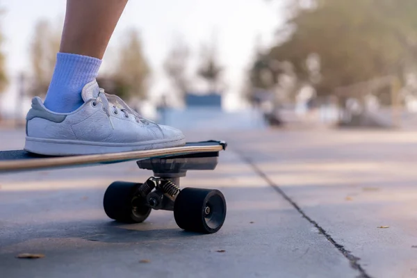 Close-up Asian women surf skate or skateboard outdoors on beautiful morning. Happy young women play surf skate at ramp park on morning time. Close up Asian women leg wear sneaker play surf skate on public park. Sport concept