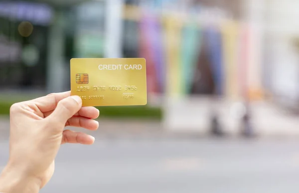 Women hand holding gold credit card member card over blur department store background. Business, shopping, lifestyle concept. With copy space