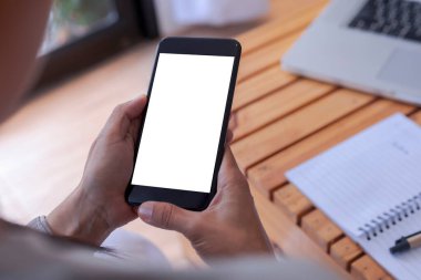 Üst görüşlü kadın elleri beyaz ekranlı akıllı telefonu tutuyor. Kadınlar atölyeye el uzatıyor, kapalı el kamerasıyla kafeteryada mesaj ve içerik için boş ekranı tutuyor.