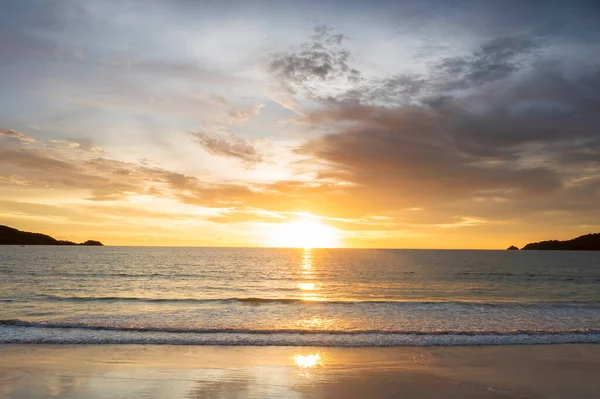 Beautiful sunset over the clam sea with cloud sky background. Sunset over tropical beach. Nature summer  concept. Peak sunset over sea with yellow light reflect on sea water. Tranquil seascape. Horizon over the water.