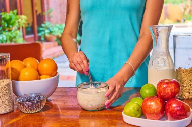 Sporcu kadın sağlıklı kahvaltı hazırlıyor mevsimlik meyveler, yoğurt, tahıl gevreği, mısır gevreği, kavun, elma, portakal, sağlıklı atıştırmalık.