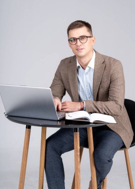 Takım elbiseli mutlu yönetici iş yerinde bilgisayar yazılımı kullanıyor. Gülümseyen erkek yönetici kameraya bakıyor. Ofiste online iş.