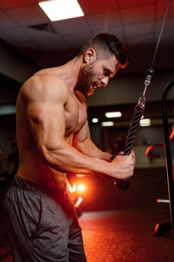 Güçlü atletik adamlar kaslarını şişiriyor. Spor malzemeleriyle antrenman yapıyorum. Vücut geliştiren kaslı biri. Spor salonunda çıplak vücutla egzersiz yapıyor. Fitness ve vücut geliştirme konsepti.