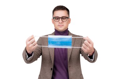 Takım elbiseli bir işadamı Covid-19 ya da Coronavirus 'tan korunmak için maske takıyor. Gri bir stüdyonun arka planında duruyor..