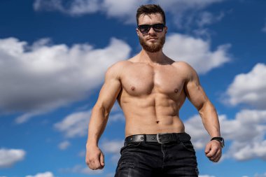 Gözlüklü, yarı çıplak vücutlu yakışıklı bir adamın portresi. Yarım boy fotoğraf. Çekici kaslı vücut. Siyah beyaz fotoğraf.