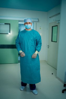 Özel koruma önlüğü giymiş bir doktor. Şapka, maske, lateks eldivenler ameliyat için hazır..