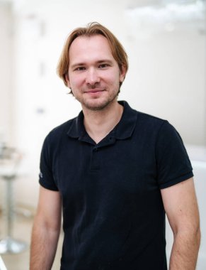 Doctor standing in office in black uniform. Medical male portrait. Medical concept. Horizontal photo.