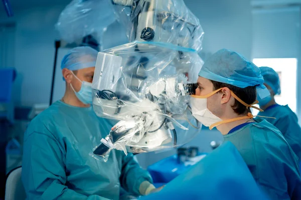 Orvosi Szakemberek Modern Műtőben Orvosok Műtétet Végeznek Megvizsgálják Mikroszkóp Működésének — Stock Fotó