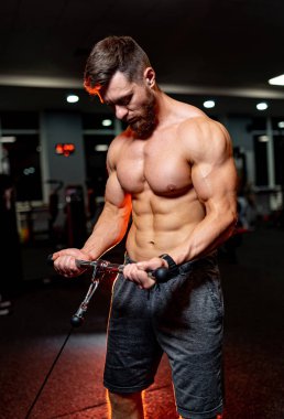 Spor salonunda mükemmel vücut trenleri olan güçlü bir erkek. Spor malzemeleriyle antrenman. Güçlü kasları olan gömleksiz bir adam..