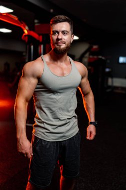 Atletik vücut. Yarı dönüşmüş manken adam karanlık arka planda kameraya poz veriyor. Güçlü kaslı adam. Yakın çekim..