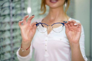 Eyeglasses closeup. Spectacles in woman's hands. Presenting glasses. Zoom in. clipart