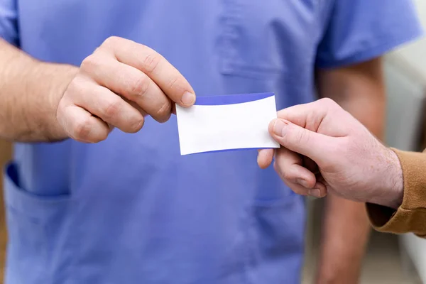 Doctor giving business card to patient. Closeup.