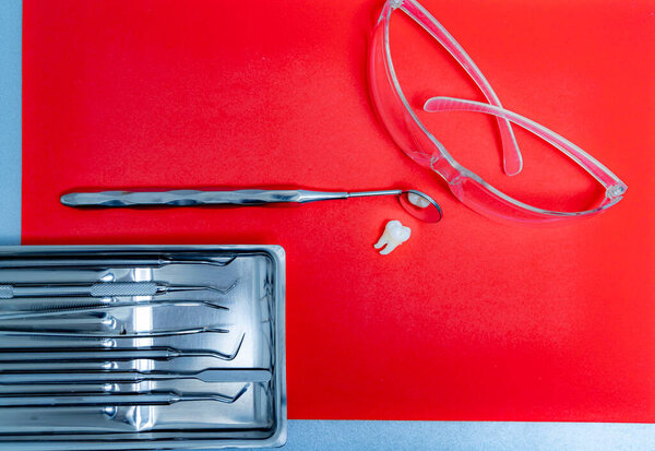 Dentist metal instruments. Stomatology concept. Red background. Selective focus.