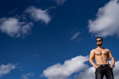 Gözlüklü, yarı çıplak vücutlu yakışıklı bir adamın portresi. Yarım boy fotoğraf. Çekici kaslı vücut. Fotoğraf aşağıdan..