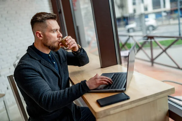 Młody Biznesmen Pijący Kawę Pracujący Laptopie Kawiarni Przystojny Mężczyzna Ciemnym — Zdjęcie stockowe