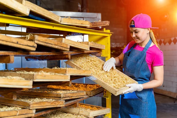 Pasta factory. Production of pasta. Krafted macaroni. Worker with wooden box with pasta.