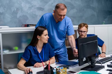 Üç doktor bilgisayarda tıbbi uzmanlığı tartışıyor. Erkek ve kadın sağlık görevlileri.