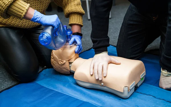 Man using CPR technique on dummy in first aid class. Oxigen mask on medical doll.