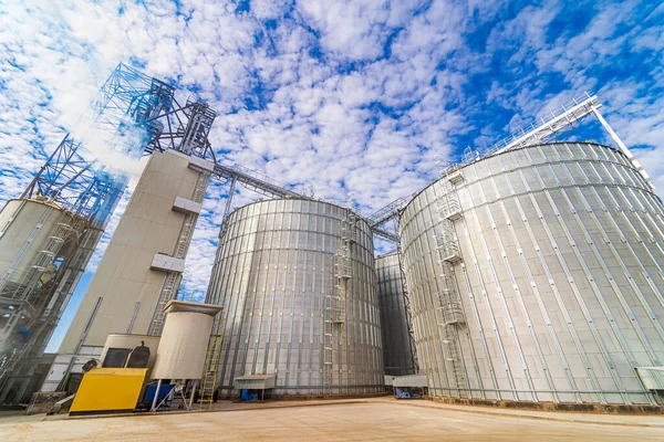 Metal grain elevators on modern factory. Crop storage in factory. Selective focus on steel constructions and technic.