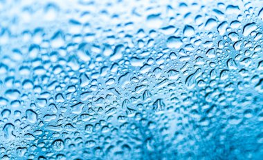 Yağmurlu günler. Pencere yüzeyine sağanak yağmur yağıyor. Pencere camına düşen yağmur damlaları. Beyaz su bardağa düşer..
