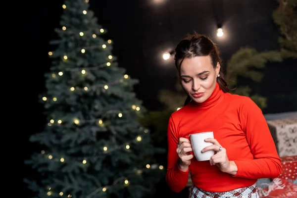 Розслаблена Жінка Червоному Светрі Позує Чашкою Гарячого Напою Біля Новорічної — стокове фото