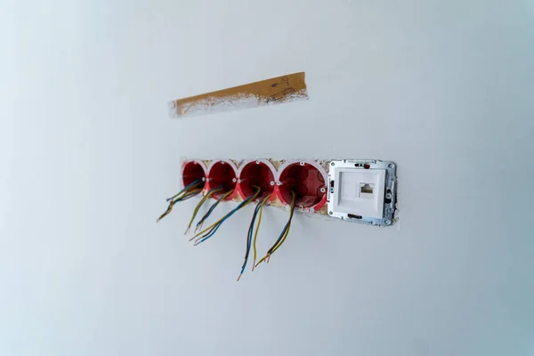 Electrical sockets and switches with the internal circuitry visible on a wall during renovation work.