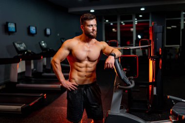 Spor salonuna karşı gömleksiz, yakışıklı, güçlü bir adamın portresi. Spor salonu. Erkek güzellik konsepti. Yakın çekim..