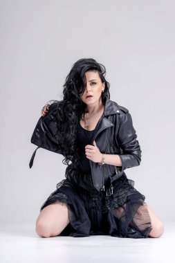 Güzel, uzun saçlı, siyah makyajlı, deri elbiseli bir kadın portresi. Beyaz arkaplanda stüdyo görüntüsü.