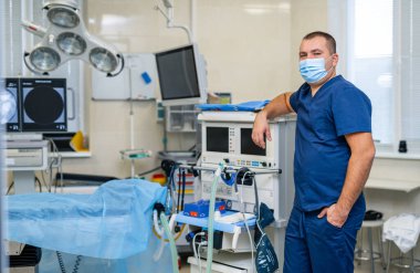 Yüzünde tıbbi maske olan bir doktor. Modern tıbbi ekipman geçmişi. Merhaba teknik ameliyat odası..